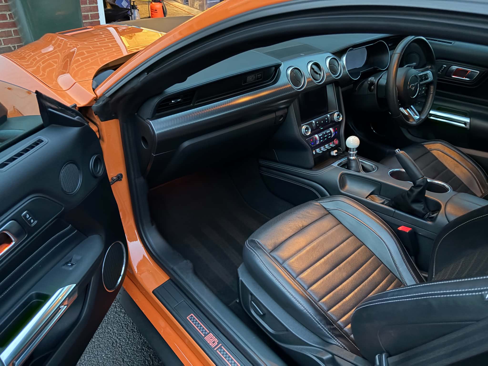 Orange Ford Mustang with its clean black leather cabin visible